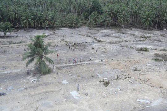 Handout shows people walking where hundreds of homes once stood in the tsunami-hit Muntei Baru Baru village, in Indonesia's Mentawai islands